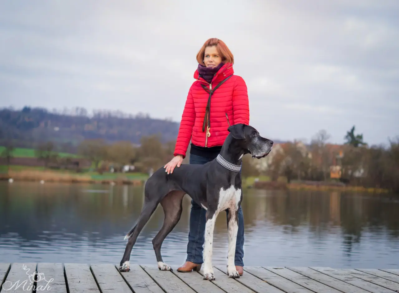 Tanja Schlipf steht mit einer Deutschen Dogge auf einem Steg am See