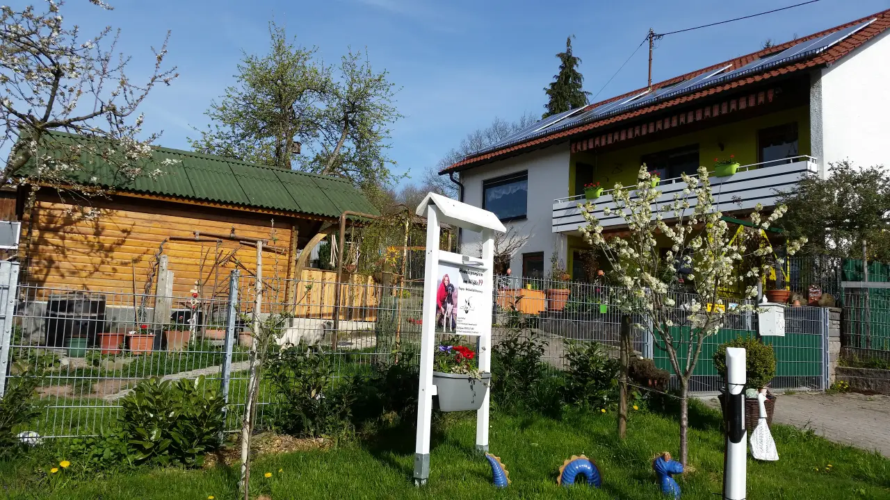 Holzhütte, Hofschild und Wohnhaus bei blauem Himmel