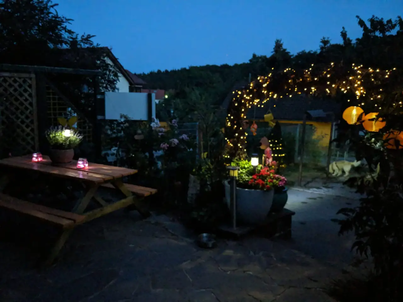 Garten in der Dämmerung mit Sitzgruppe und Lichterbogen
