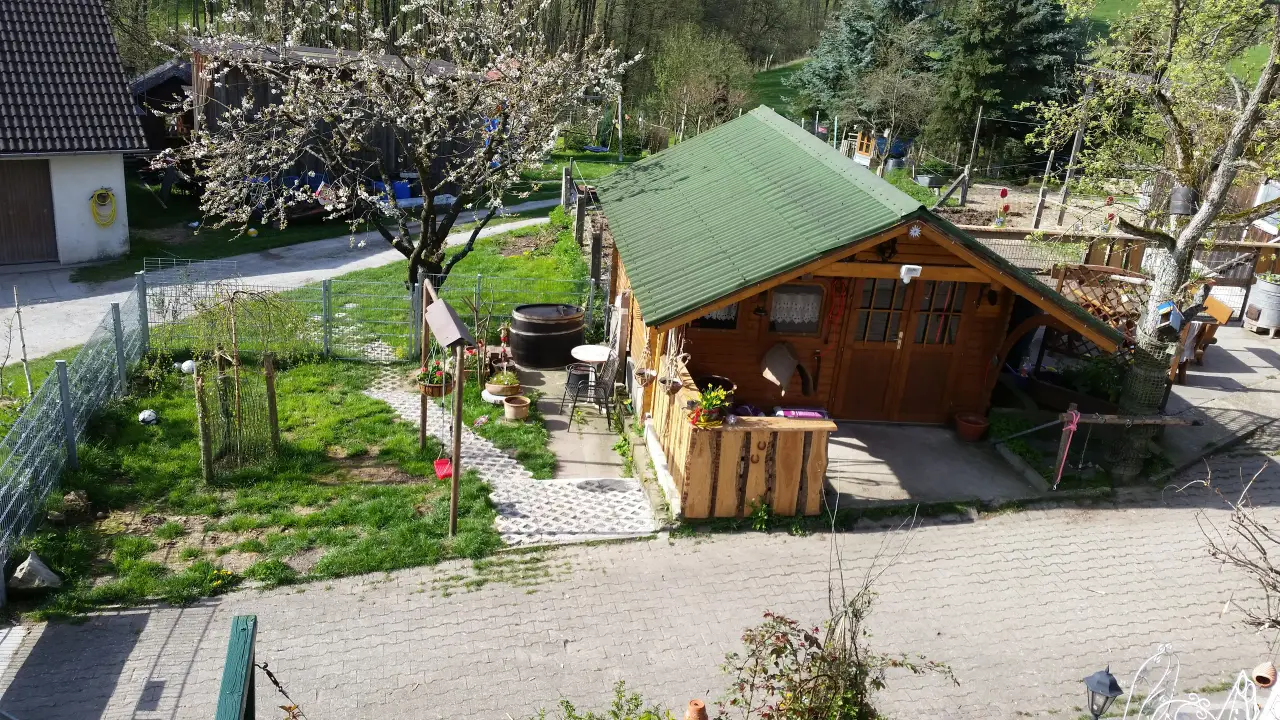 Blick von oben auf die Holzhütte mit grünem Dach und den Garten