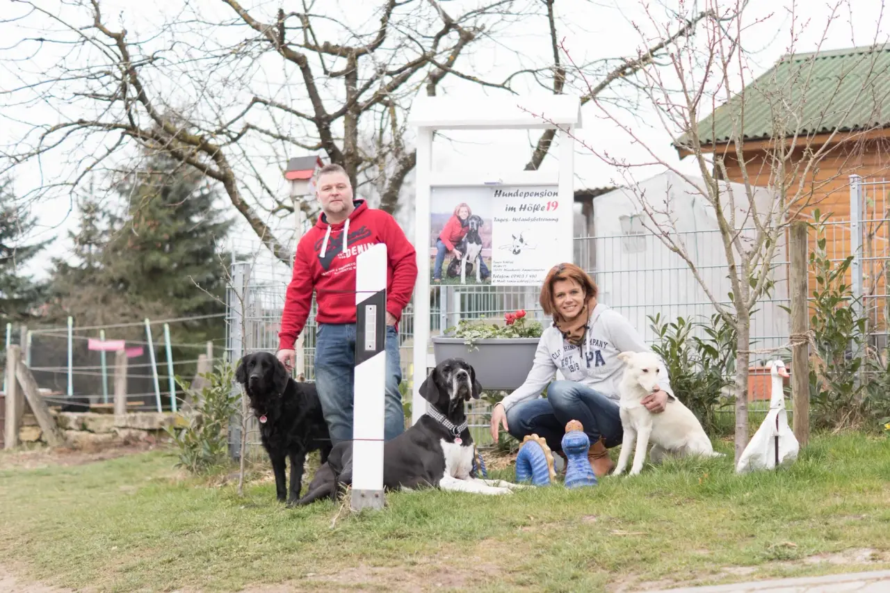 Die Familie Schlipf mit mehreren Hunden vor dem Hofschild